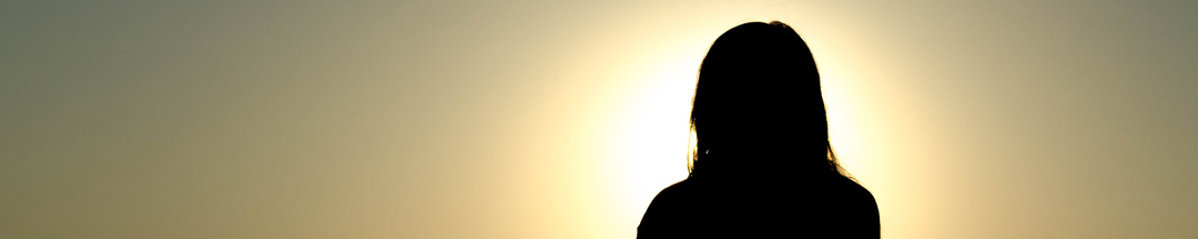 A silhouette of a person meditating at dawn.