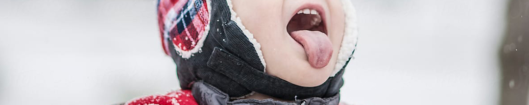 A kid catching snowflakes with their tongue.
