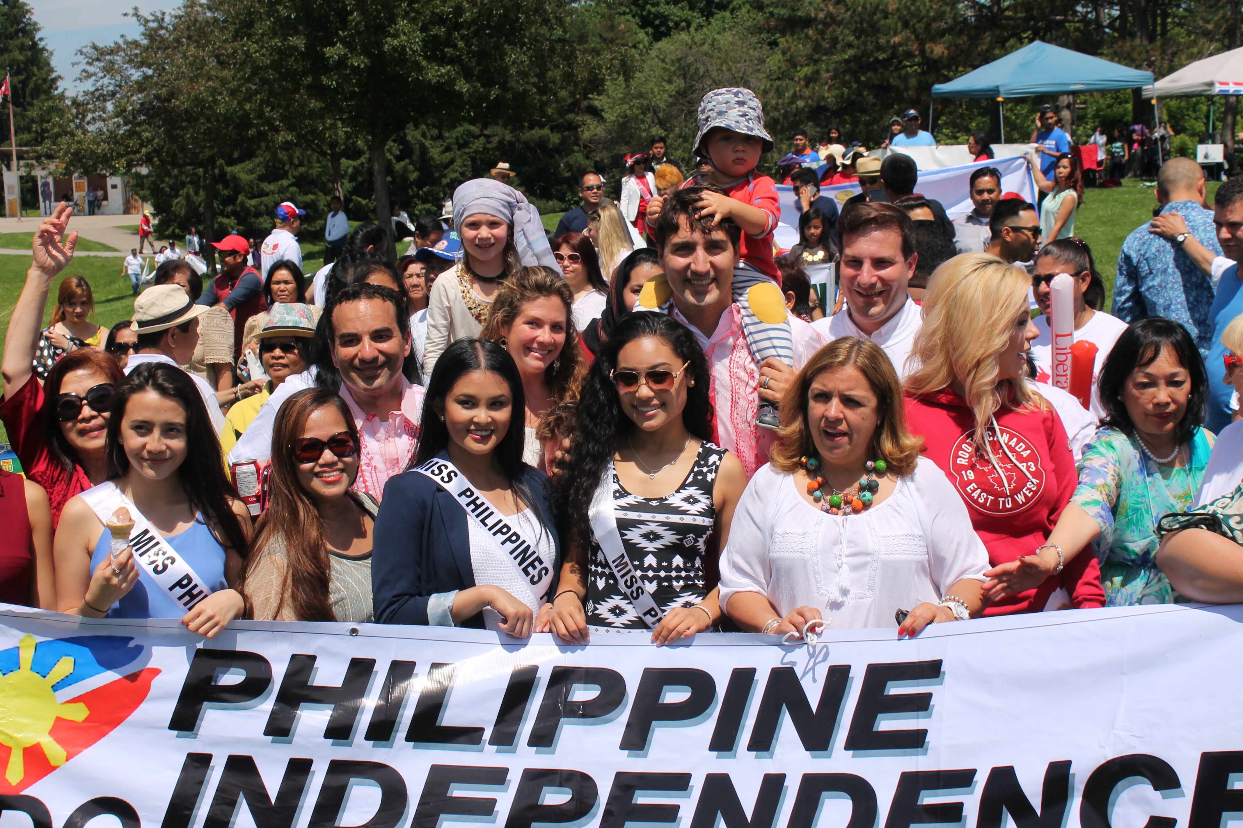 A group of people, including Prime Minister Justin Trudeau, holding a banner at a park.