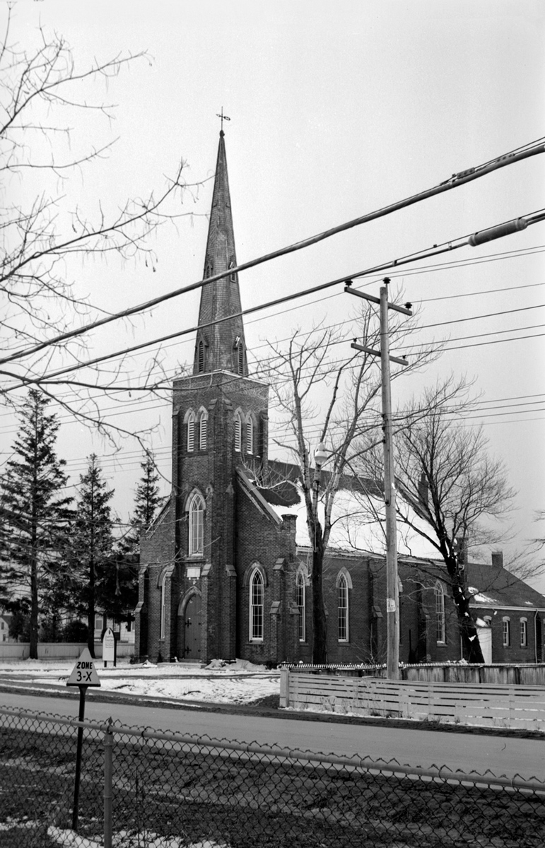 A black and white photo of a church, taken from across the street.