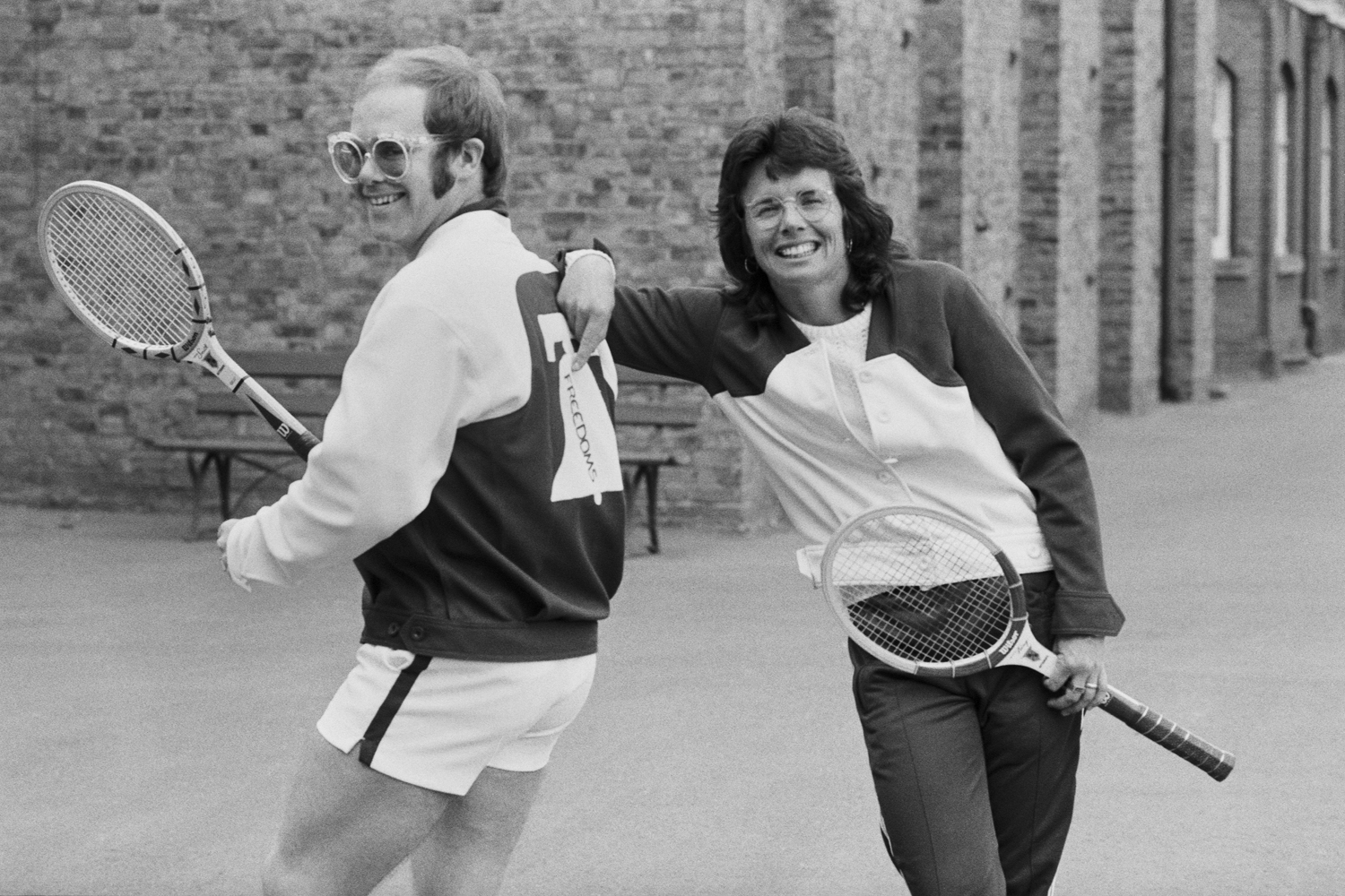 A black and white photo of Elton John and Billie Jean King holding tennis rackets.