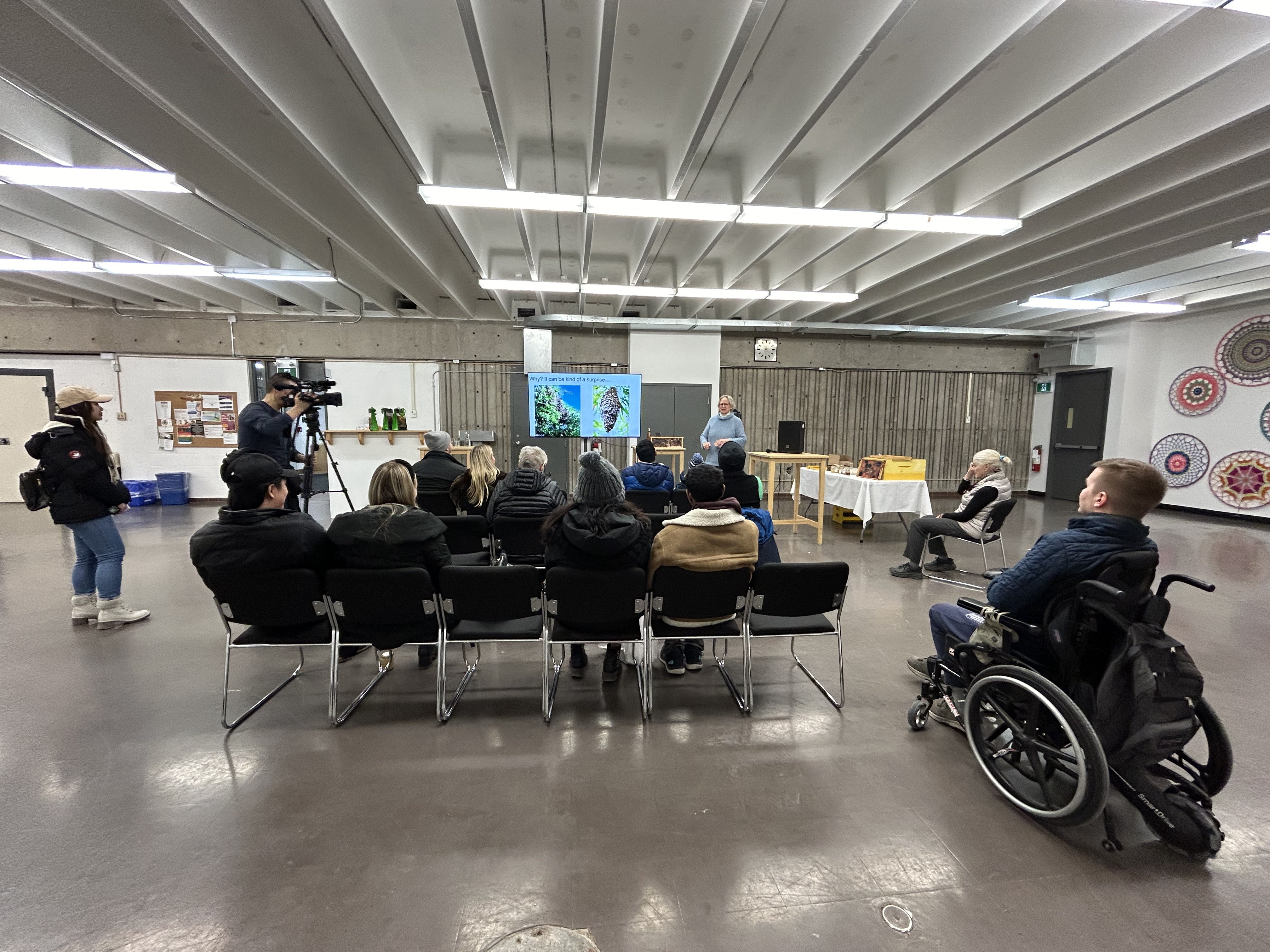 A group of people in a room watching a TV and presenter in a workshop
