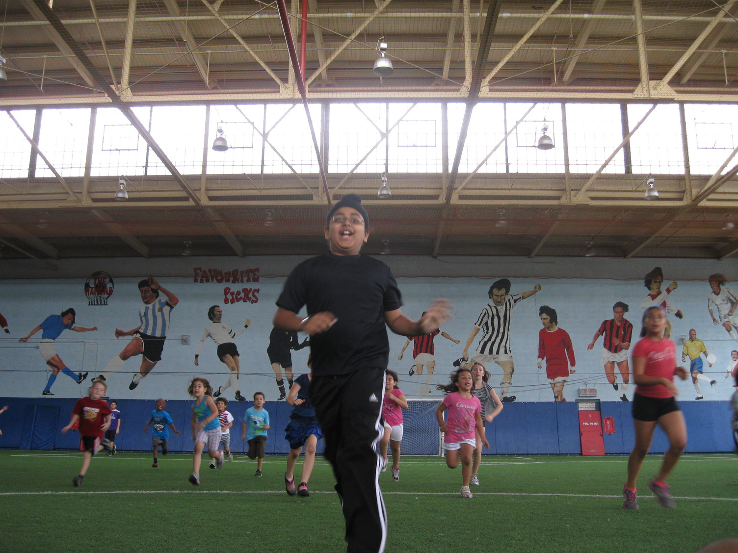 Kids running on an indoor soccer field.