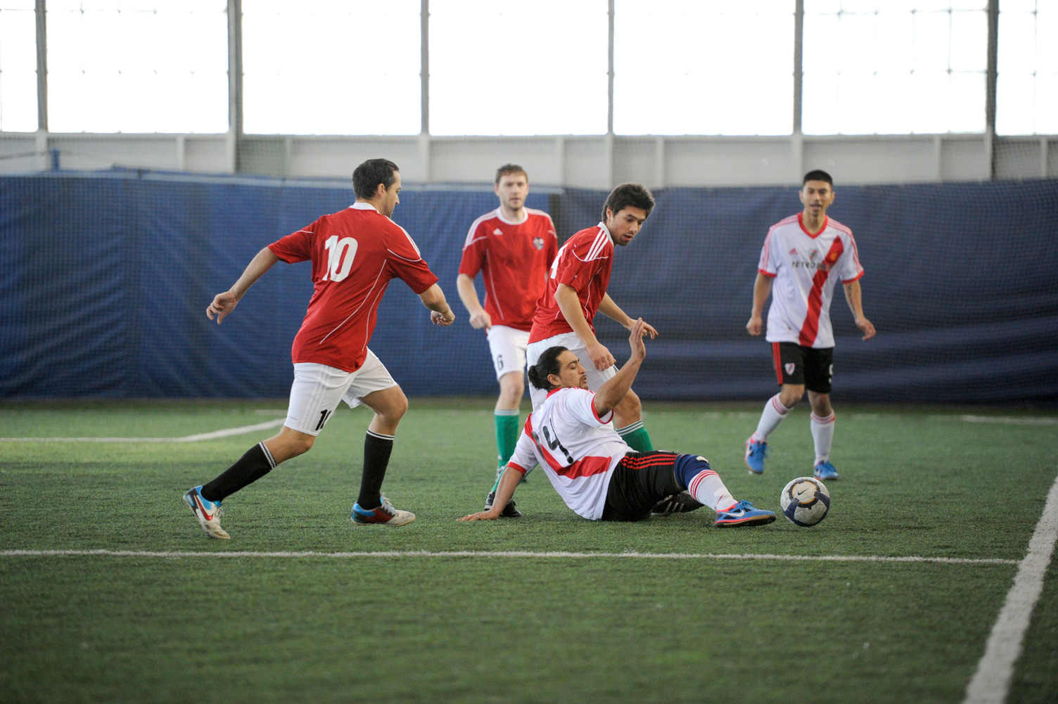 People playing soccer on an indoor field.