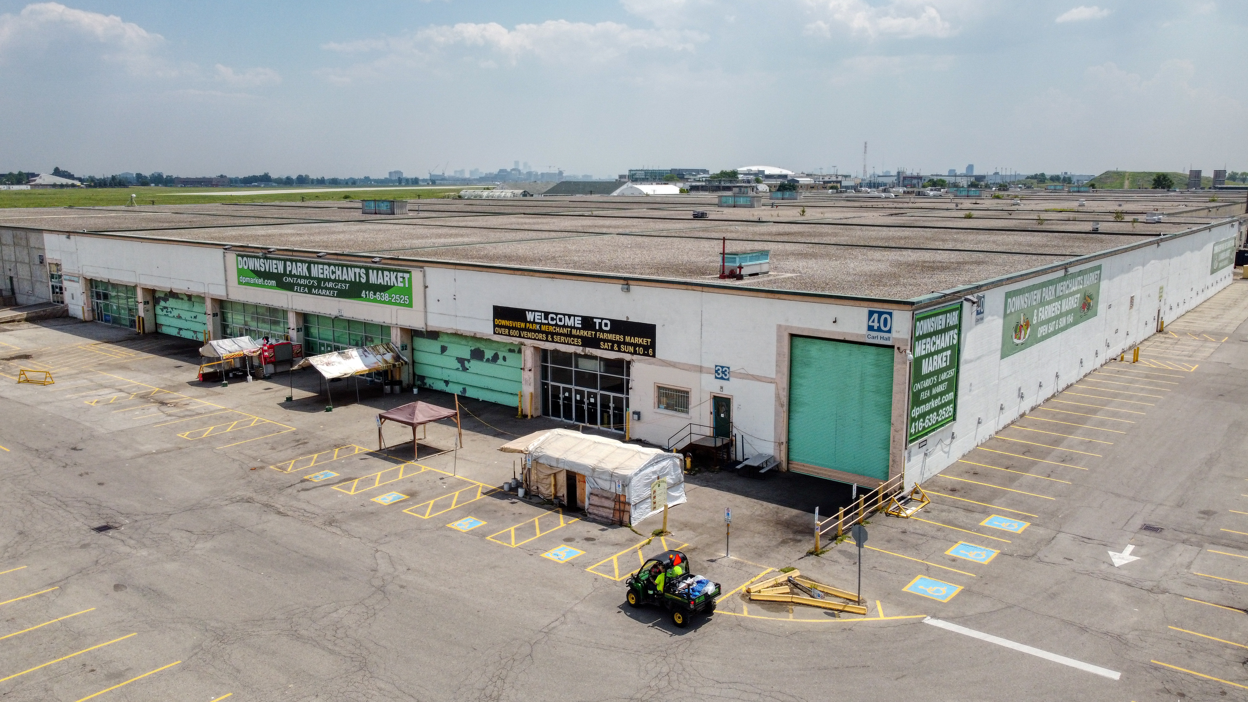 An aerial shot of a large one-storey building with a green sign that says &quot;Downsview Park Merchants Market&quot;.