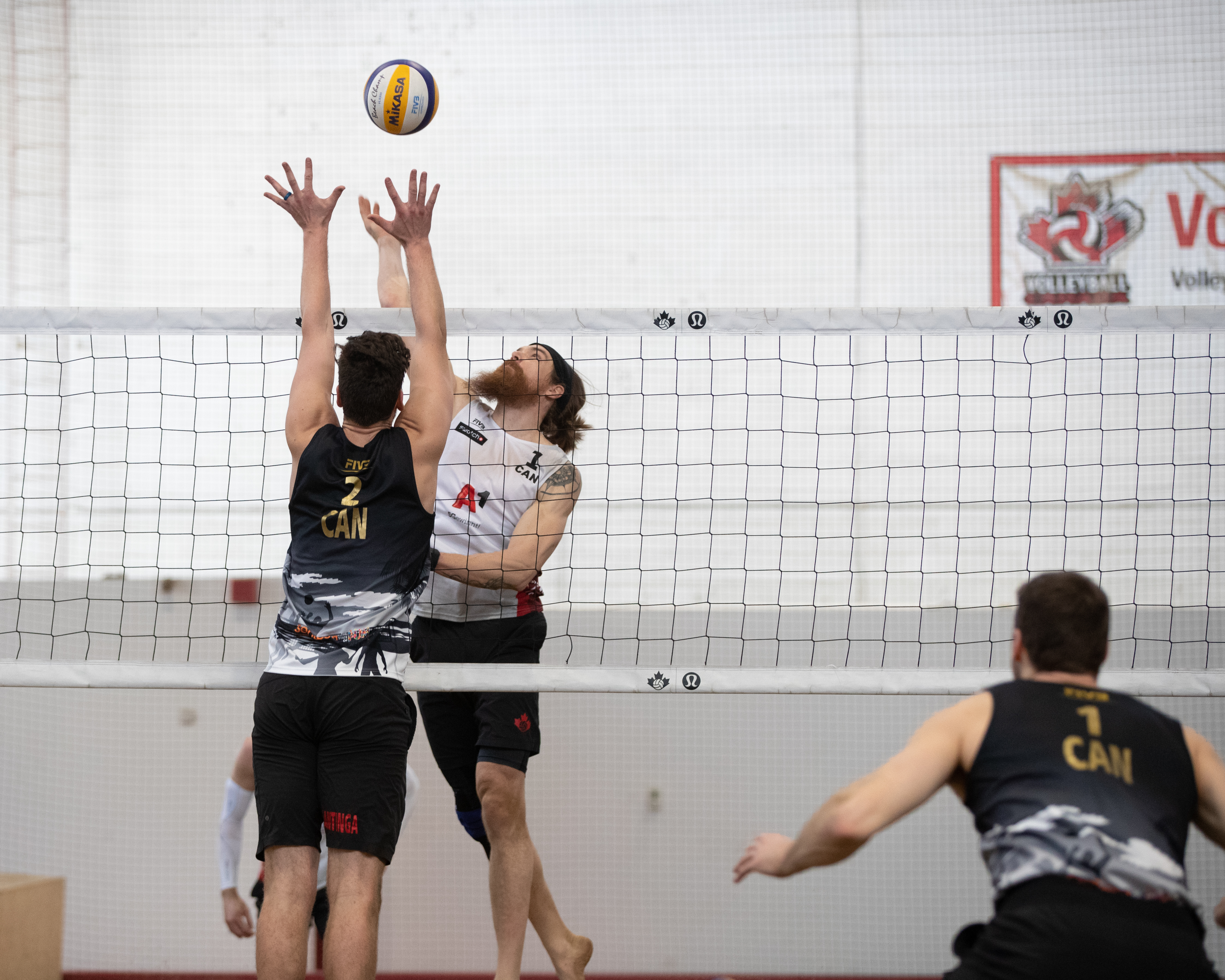 Three athletes playing volleyball inside Volleyball Canada's facility.