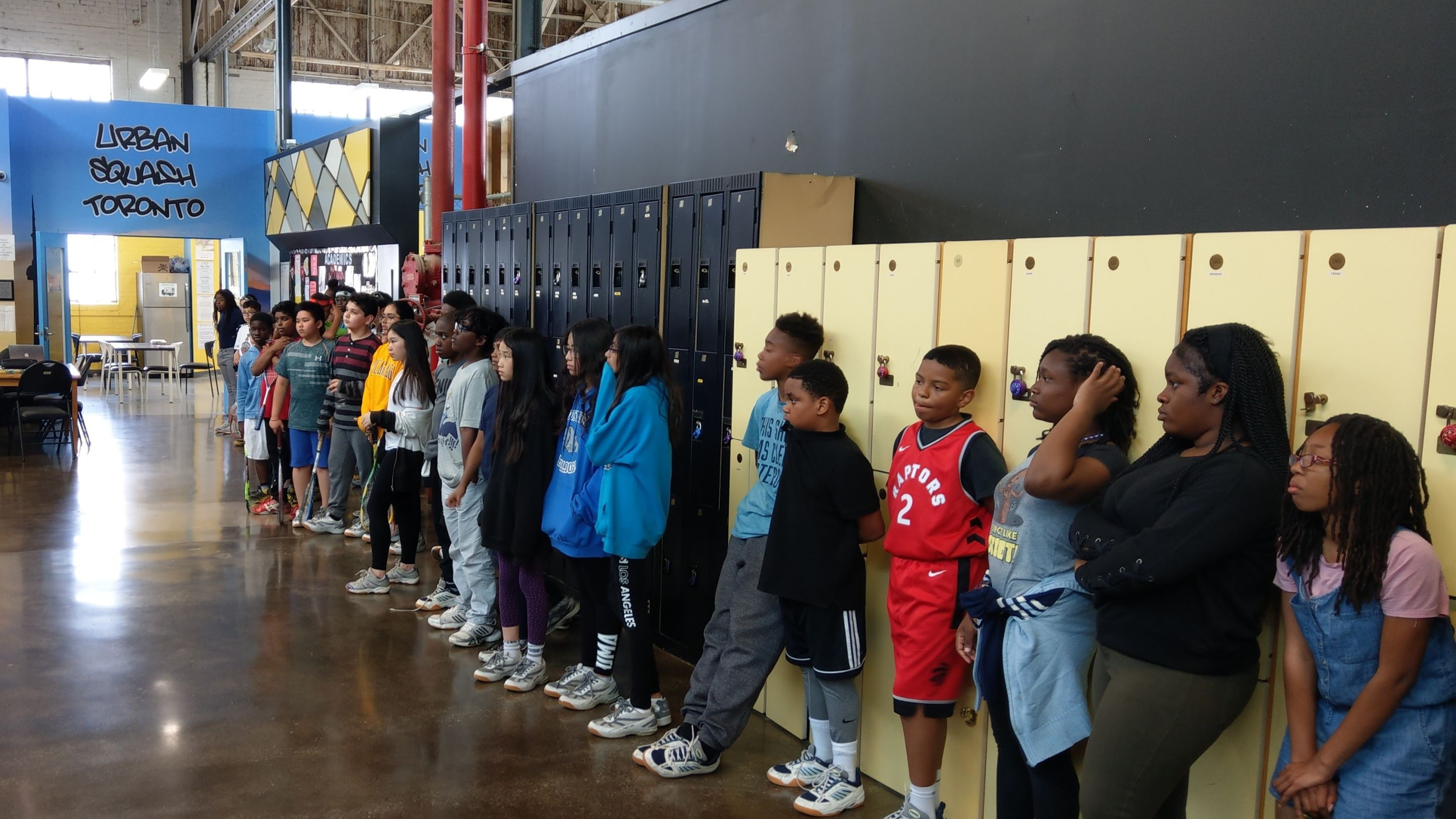Kids and youth lined up along some lockers.