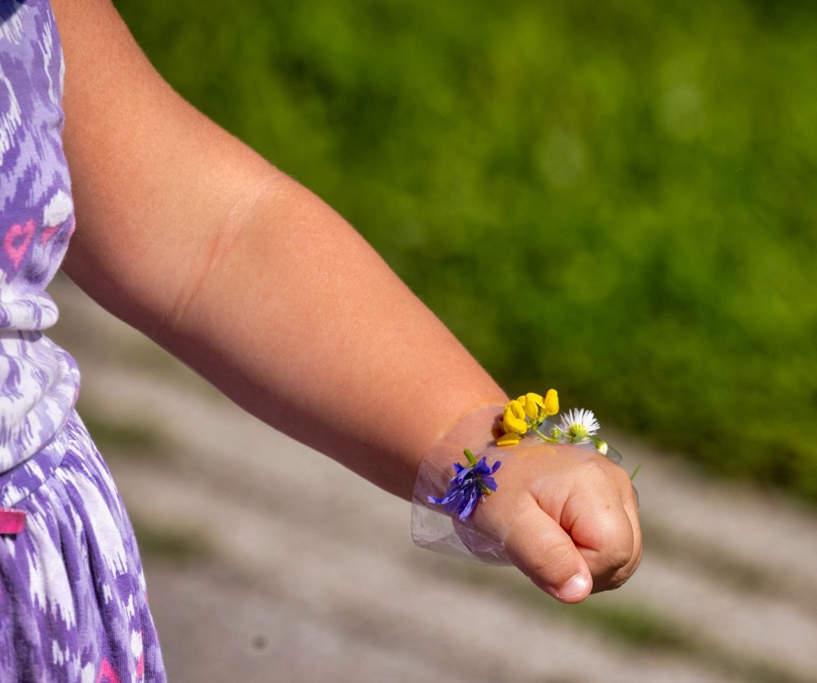 A child wearing a bracelet made out of flowers.