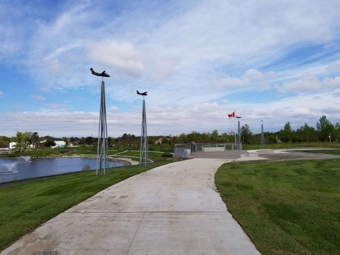 Model planes along a paved path that overlooks a body of water.