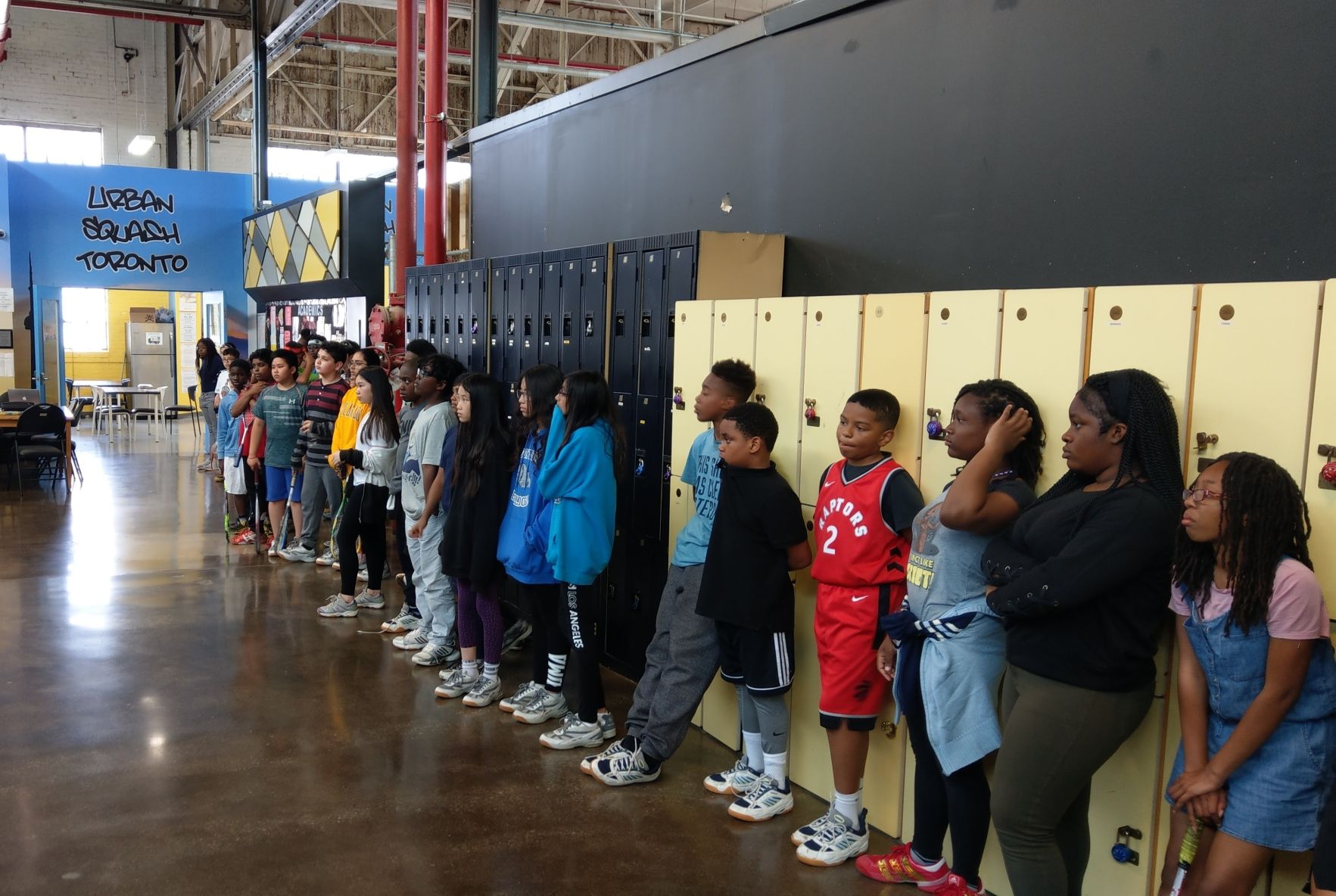 Kids and youth lined up along some lockers.