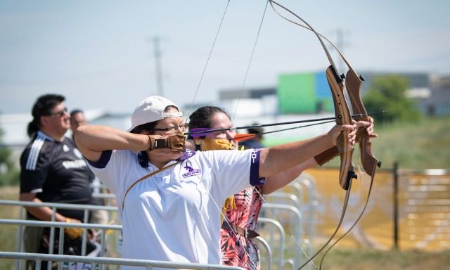 Two athletes in an archery competition, aiming their arrows at a target.
