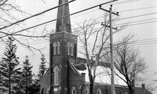 A black and white photo of a church, taken from across the street.