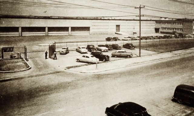 A black and white photo of cars parked outside of a building along Carl Hall Road.