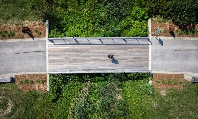 An aerial shot of a person walking on a pedestrian bridge.