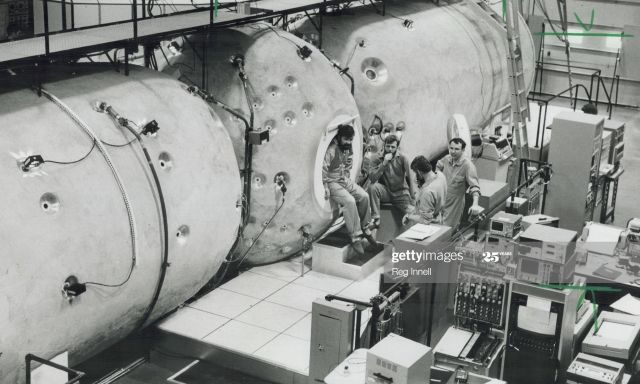 A black and white photo of a crew in front of machinery.