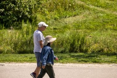 An elderly couple walking on a paved trail.