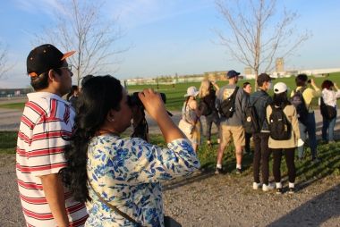 A group of people looking through binoculars on a birding walk.