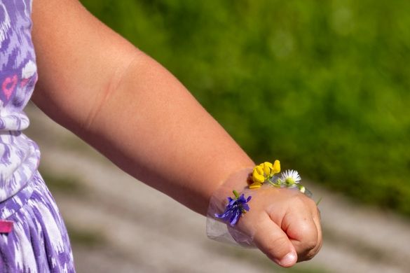 A child wearing a bracelet made out of flowers.
