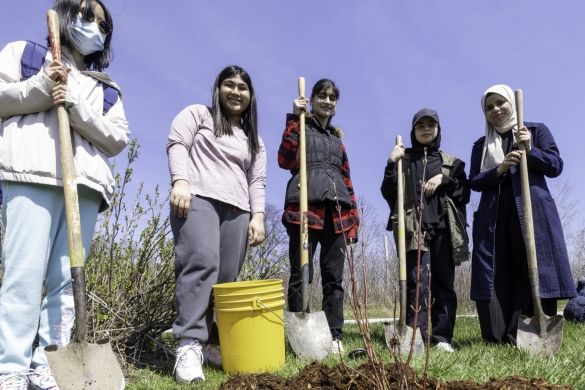 A group of people posing with their shovels at the tree planting site.