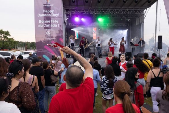 A crowd of people dancing and waving Canadian flags in front of the stage