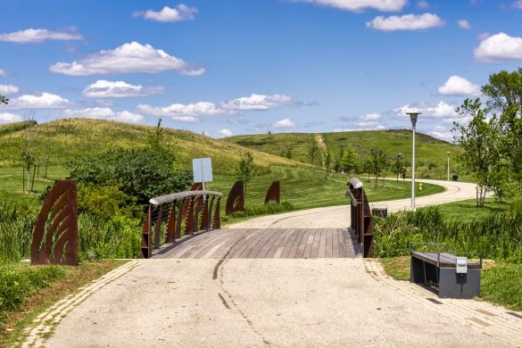 A pedestrian bridge along a paved trail. Below it is a wetland.