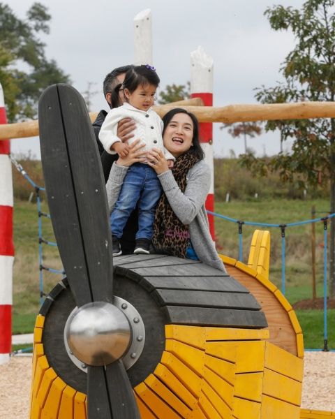 A mom playing with her kid in the yellow model plane at the Play Zone.