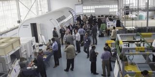 Staff and students gathered indoors around part of a Bombardier aircraft.