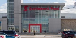 A modern glass building with an entrance outlined in red.